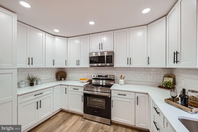 kitchen featuring white cabinets, light wood-style floors, stainless steel appliances, and light countertops