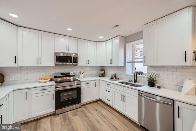 kitchen featuring appliances with stainless steel finishes, white cabinets, visible vents, and a sink