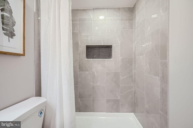 bathroom featuring toilet and a tile shower