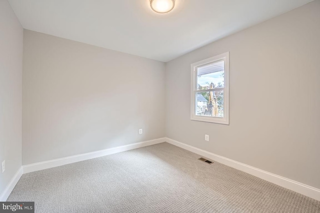 unfurnished room featuring carpet, visible vents, and baseboards