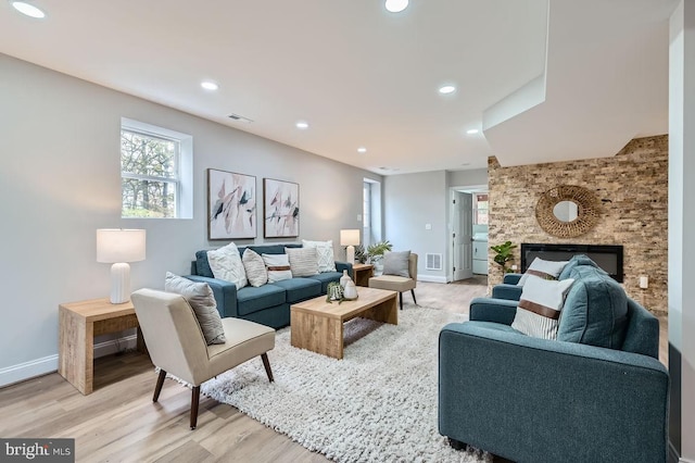 living room with light wood finished floors, recessed lighting, visible vents, a large fireplace, and baseboards