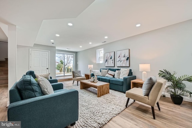 living area with recessed lighting, baseboards, light wood finished floors, and stairs