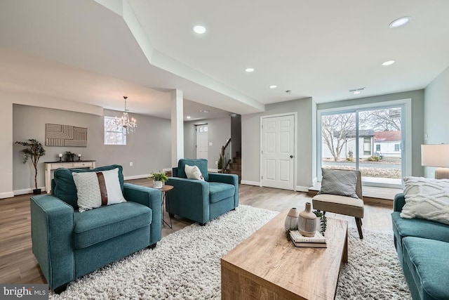 living area featuring a wealth of natural light, stairs, wood finished floors, and recessed lighting