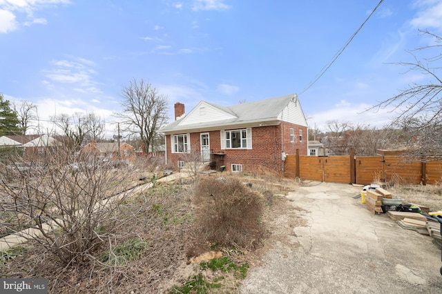 view of front of home with brick siding, a chimney, a gate, and fence