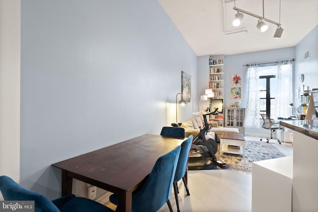 dining area featuring track lighting, visible vents, and wood finished floors