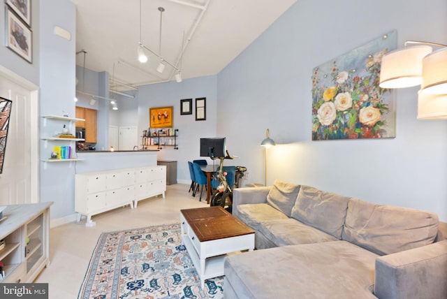 living room featuring baseboards, a high ceiling, rail lighting, and attic access