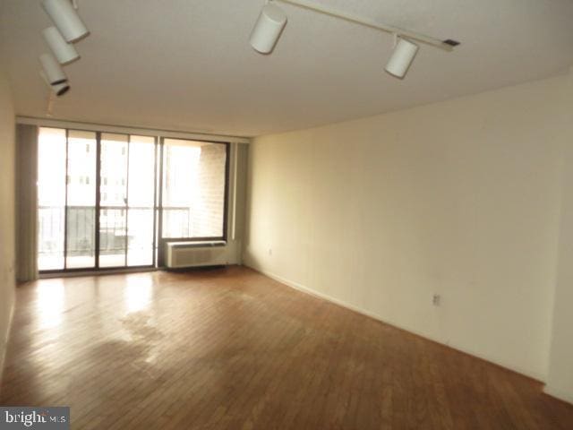 unfurnished room with a wall of windows and wood finished floors