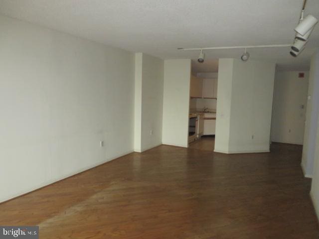 empty room featuring rail lighting and wood finished floors