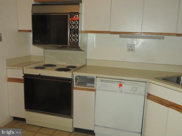 kitchen featuring black microwave, electric stove, white dishwasher, and white cabinets