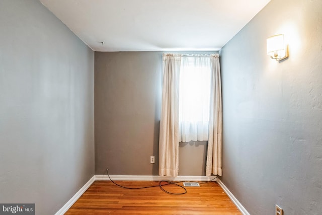 empty room featuring light wood-type flooring, visible vents, and baseboards