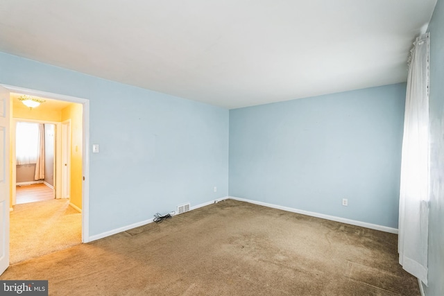 carpeted spare room featuring visible vents and baseboards