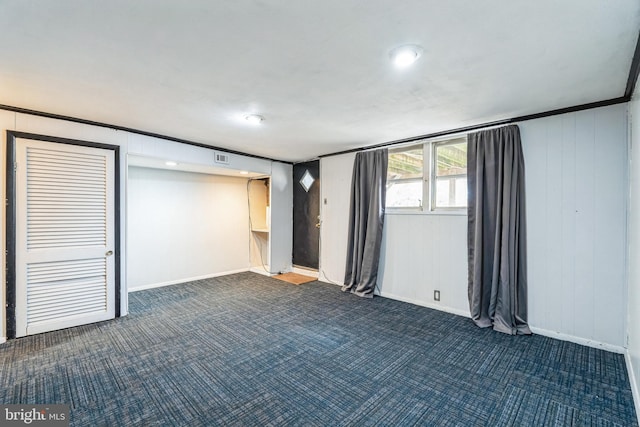 spare room featuring baseboards, visible vents, and dark carpet