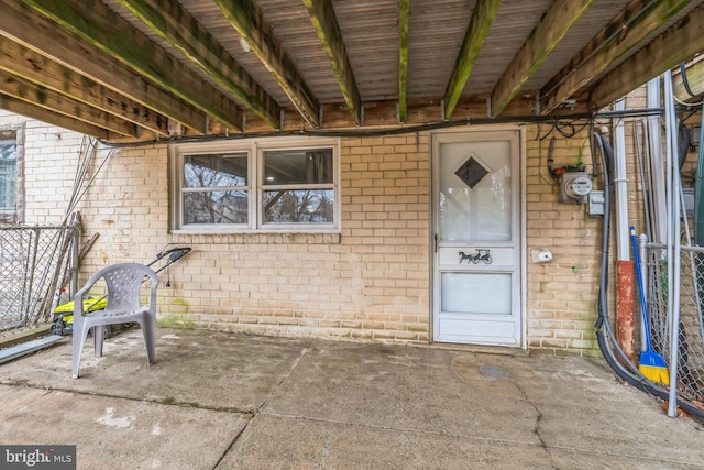 view of exterior entry featuring brick siding and fence