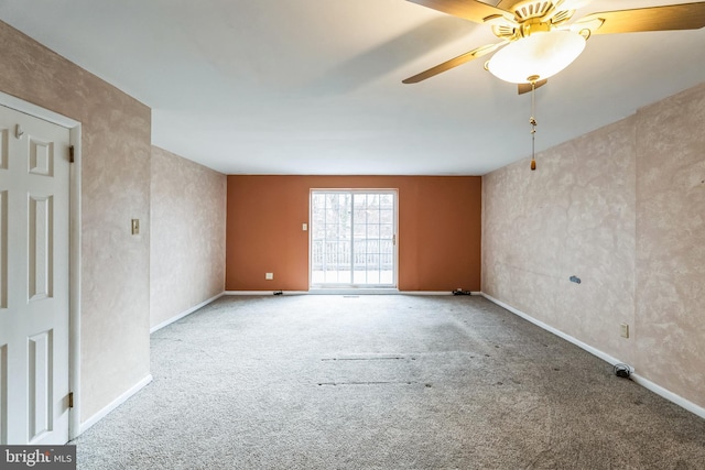 carpeted spare room featuring baseboards and a ceiling fan