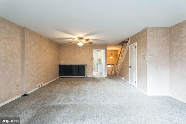 unfurnished living room with ceiling fan, carpet, and visible vents