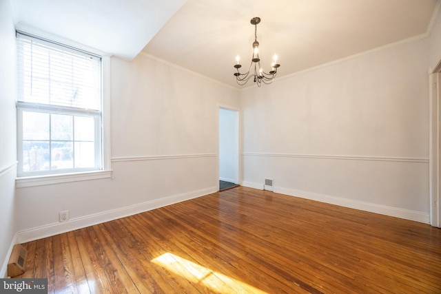 unfurnished room featuring visible vents, a notable chandelier, hardwood / wood-style flooring, crown molding, and baseboards