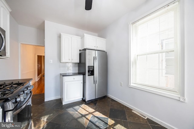 kitchen with visible vents, backsplash, white cabinetry, appliances with stainless steel finishes, and baseboards