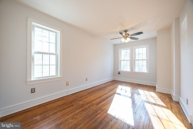 empty room featuring hardwood / wood-style flooring, a ceiling fan, baseboards, and a wealth of natural light