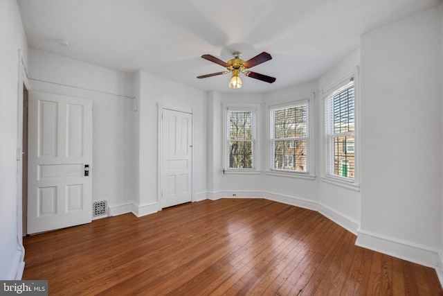 unfurnished bedroom featuring ceiling fan, visible vents, baseboards, and hardwood / wood-style floors