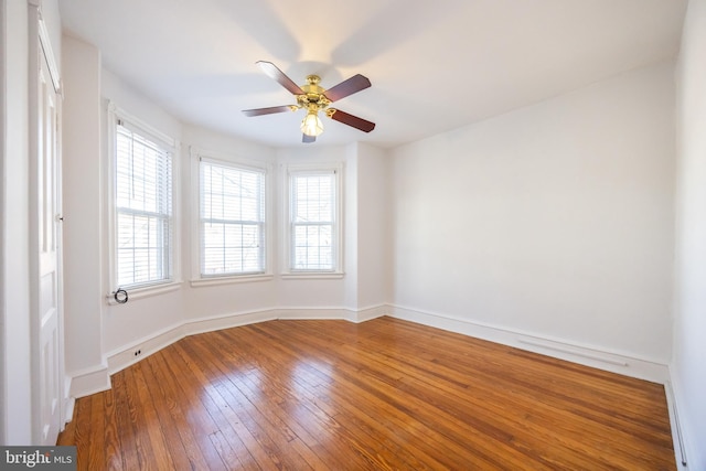 empty room with ceiling fan, baseboards, plenty of natural light, and hardwood / wood-style floors