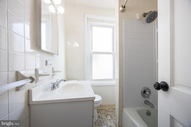 full bath featuring vanity, tile walls, toilet, and washtub / shower combination