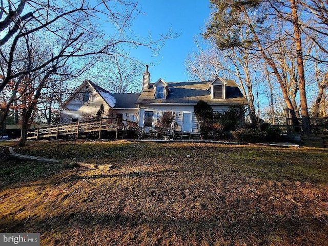 back of property featuring a lawn, a chimney, and fence