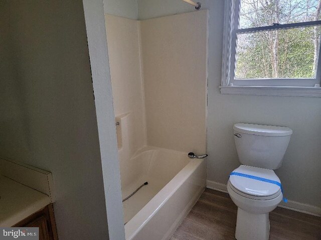 bathroom with shower / bath combination, baseboards, toilet, and wood finished floors