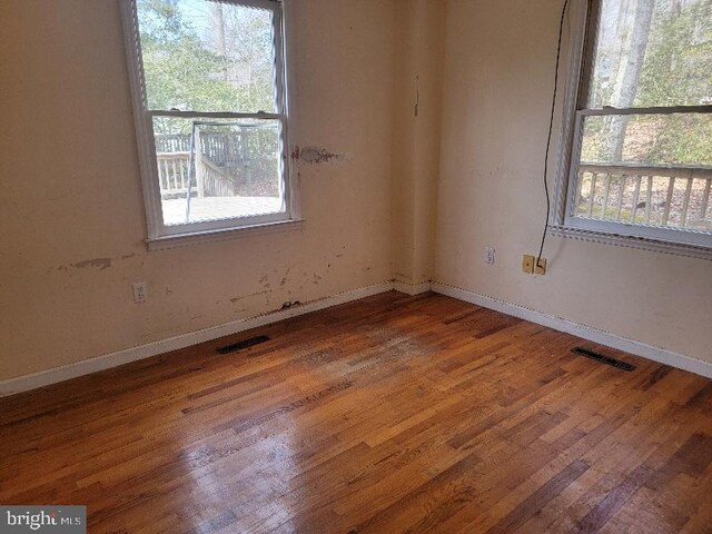 unfurnished room featuring visible vents, baseboards, and hardwood / wood-style flooring