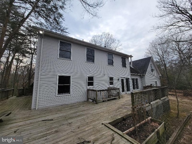 rear view of property with a garden and a wooden deck