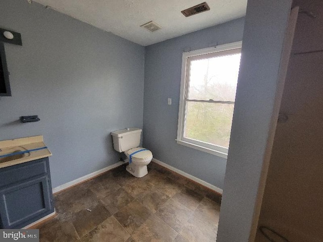 bathroom featuring baseboards, toilet, and a healthy amount of sunlight