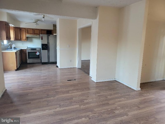 kitchen featuring a sink, stainless steel appliances, wood finished floors, and brown cabinetry