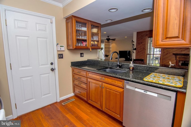 kitchen featuring brown cabinetry, visible vents, a sink, light wood-style floors, and stainless steel dishwasher