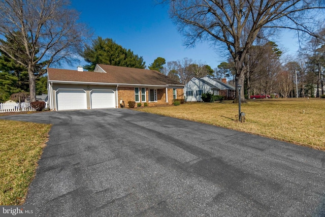 single story home with a front yard, brick siding, a garage, and driveway