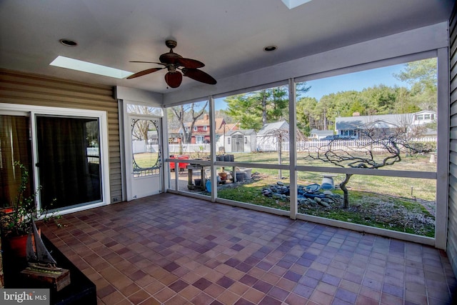 unfurnished sunroom with a skylight and ceiling fan