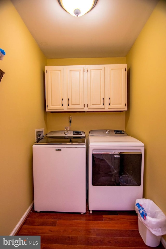 washroom with cabinet space, washer and dryer, baseboards, and dark wood-style flooring