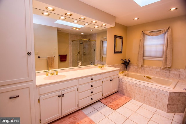 bathroom featuring a shower stall, a skylight, a garden tub, and a sink