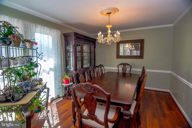 dining room with ornamental molding, wood finished floors, baseboards, and a chandelier