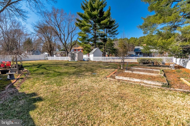 view of yard with an outbuilding, a vegetable garden, a storage unit, and a fenced backyard