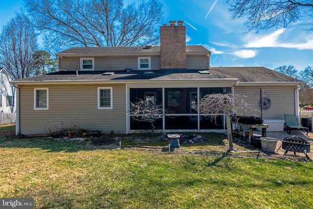 rear view of property featuring a chimney, a lawn, a fire pit, and a sunroom