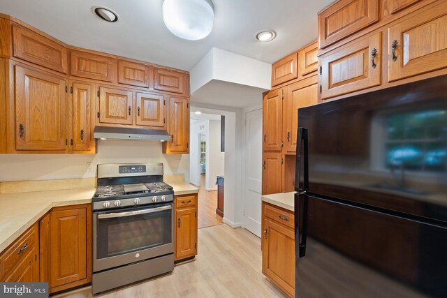 10402 Hayes Ave, Silver Spring, MD 20902 - kitchen featuring freestanding refrigerator, gas range, under cabinet range hood, light wood finished floors, and light countertops