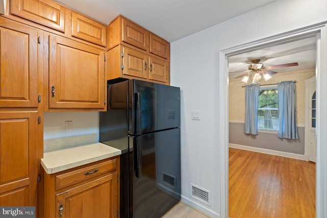 10402 Hayes Ave, Silver Spring, MD 20902 - kitchen with freestanding refrigerator, light wood-type flooring, ceiling fan, light countertops, and brown cabinets