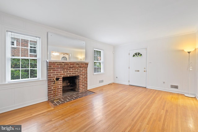 10402 Hayes Ave, Silver Spring, MD 20902 - unfurnished living room with wood finished floors, ornamental molding, a decorative wall, and a brick fireplace