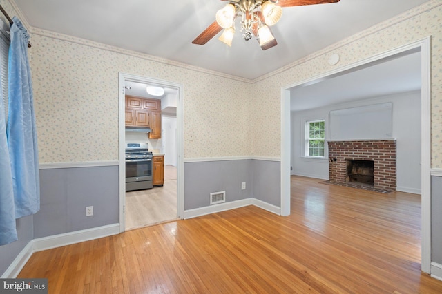 10402 Hayes Ave, Silver Spring, MD 20902 - unfurnished living room featuring ceiling fan, light wood finished floors, a wainscoted wall, a brick fireplace, and wallpapered walls