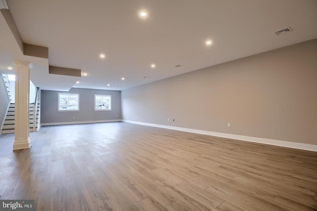 unfurnished living room with baseboards, light wood-type flooring, and ornate columns