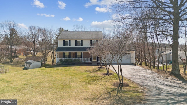 view of front of property featuring driveway, a porch, an outdoor structure, a front lawn, and a storage shed