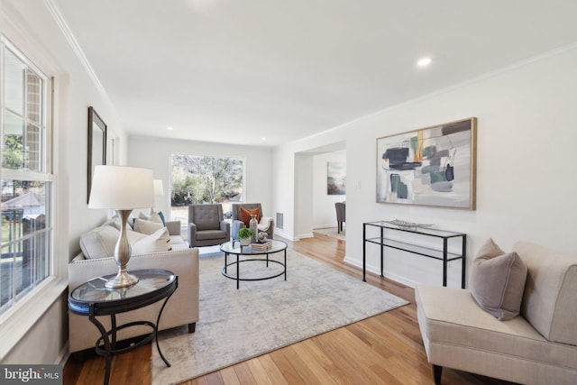 living area with wood finished floors, visible vents, baseboards, recessed lighting, and ornamental molding