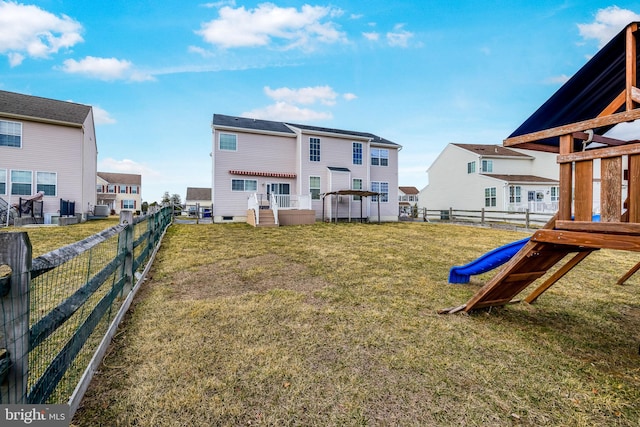 back of property with a yard, a residential view, and fence