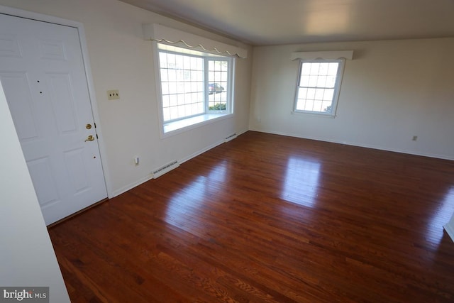 foyer with wood finished floors, visible vents, and baseboards