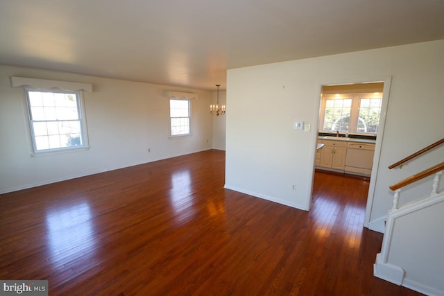 unfurnished room featuring baseboards, a notable chandelier, dark wood-style floors, and stairs