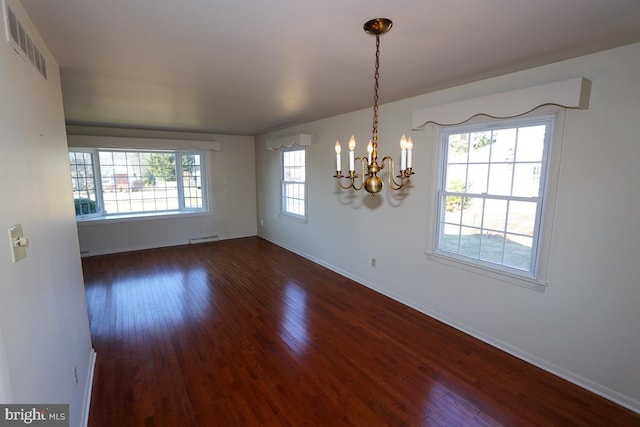 spare room featuring an inviting chandelier, baseboards, dark wood-style flooring, and visible vents